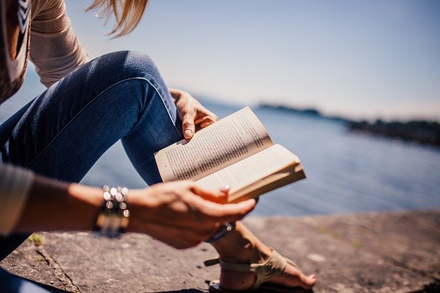 Chica leyendo junto al mar